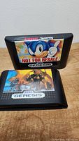 Sonic the Hedgehog cartridge labeled Not For Resale on top of Altered Beast cartridge on wooden surface.