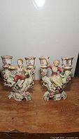 Full view of both porcelain figurine double candle holders, boy and girl, showing vintage condition and floral details.