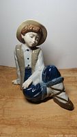 Front view of the Nadal porcelain figurine showing sitting boy in detailed clothing and hat