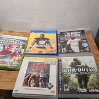 Overview photo showing all 5 games laid flat: Xbox 360 Ultimate Alliance, PS4 Madden NFL 19, PS3 MLB 08 The Show, Call of Duty 4 Modern Warfare, and Tekken 6 with visible cases and artwork.