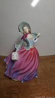 Front angled view of the full figurine showing the lady in colorful dress and bonnet.