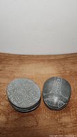 Front and back view of two hand carved grey stone Egyptian scarab paperweights showing hieroglyphic engravings and polished surfaces.