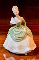 Front view of vintage Royal Doulton Soiree figurine in green and white dress holding a fan.