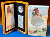 Wooden display case opened showing Canadian silver coin and two $2 stamps mounted on black velvet. Coin features Sable Island horses, with illustrated backing and outer cardboard packaging.
