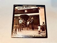 Front cover of Willy and the Poor Boys album by Creedence Clearwater Revival showing the band playing outside Duck Kee Market with children watching.