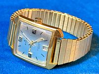 Angle view of the Edox Hydromatic 1000 watch showing square gold-tone case, silver dial with date at 3 o'clock, and expandable gold-tone bracelet.