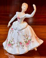 Front view of Royal Doulton Shirley figurine showing full dress with pink floral pattern and raised right arm.