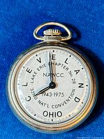 Front face of the vintage pocket watch showing detailed dial text including Lake Erie Chapter No. 28, NAWCC, Cleveland Ohio, 1943-1975 dates and 32nd National Convention.
