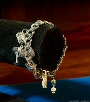 Side-angle view of the sterling silver chain bracelet with visible charms including a martini glass, handbag, gift box, and a dangling round charm.