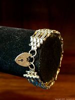 Side view on black display stand showing interlocking gate links and heart padlock clasp