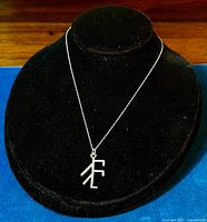 Full view of sterling silver pendant necklace on black bust with Viking rune symbol.
