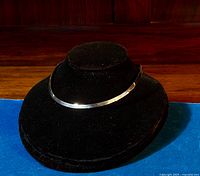 Sterling silver choker necklace displayed on black velvet bust, showing shine and curvature.