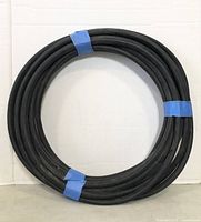 Front view of the coiled 25-foot black rubber water hose secured with blue tape.