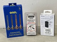Three packaged electronics items: Sony FM/AM radio box, Scosche antenna adapter, onn AirTag protective holders