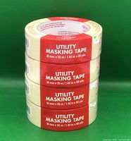 Four stacked rolls of utility masking tape with red and white labels showing dimensions 36 mm x 55 m / 1.42 in x 60 yds.