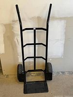 Front view of black heavy duty hand truck with steel frame and wide toe plate.