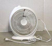 Front view of white portable table fan showing circular grill and power cord