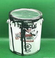 Tremclad rust paint can with black paint drips on exterior, 3.78L, gloss black paint and primer in one. Can is dented and paint stained but full.
