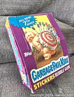 Front and side view of the original Garbage Pail Kids 7th series trading card box with colorful artwork and branding visible.