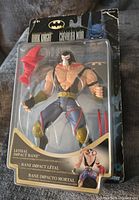 Bane action figure in original packaging showing front and blister pack with figure and accessories.