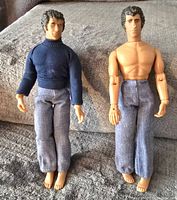 Two MEGO Starsky & Hutch dolls, one fully dressed, one shirtless, wearing pants, shown front view on grey textured surface.