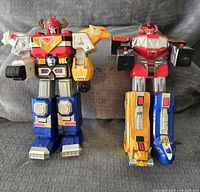 Front view of two vintage Megazord figures, one with bull motif and one with horned head, showing colors and details.