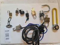 Photo showing 11 assorted locks including padlocks with keys, combination locks, and cable lock with combination mechanism, arranged on white background with MaxSold tag visible.