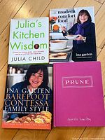 Four cookbooks stacked showing covers of Julia's Kitchen Wisdom, Modern Comfort Food, Barefoot Contessa Family Style, and Prune.
