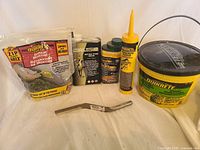 Full lot showing all concrete repair materials and tools including Quikrete bucket, repair tube, mortar mix bag, stone sealers, and metal brick joiner tool