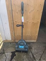 Full view of black Yardworks electric snow shovel standing upright, showing the handle and main body.