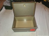 Open metal security box showing interior, hinged lid, and chain inside