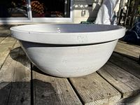 Side view of white ceramic pot placed on wooden deck, showing shape and finish.