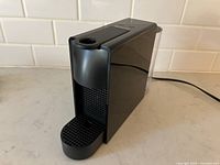 Front view of the black Nespresso Essenza Mini coffee machine showing the capsule insertion area and drip tray