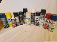 Front view of spray paint cans lined up in a row showing various brands and types including Rust-Oleum and Dupli-Color.