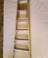 Top view of the ladder showing the four wide steps and the top platform with a ruler for scale to approximately 6 feet.