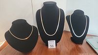 Three sterling silver chains displayed on black stands showing different designs and lengths of each chain.