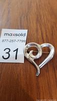 Front view of sterling silver heart brooch on wood background with MaxSold lot tag visible.