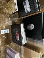 Photo showing black photo albums with oval window cutouts on top and side of pile on marble surface.