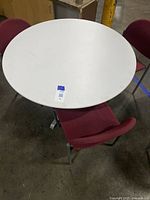 Overhead view of the 42-inch round table with three maroon fabric chairs around it, showing table surface and chair upholstery.