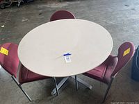 42-inch diameter round white composite table with 3 red fabric chairs around it, showing the overall lot contents.