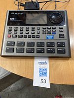 Front view of Alesis SR18 Drum Machine with power supply visible, showing buttons, pads and dial.