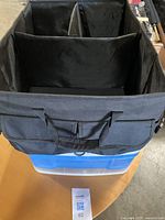 Black collapsible fabric storage organizer trunk with three compartments shown from above, highlighting interior dividers and handles.