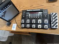 Top view of Fender Frontman 10G amp and DigiTech RP1000 multi-effects pedal on a wooden surface showing multiple footswitches and knobs on the pedal.