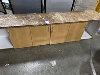 Front view of the office table showing brown marble top and four wooden cabinet doors with handles.