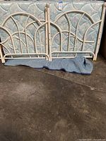 Cream metal floral twin bed and trundle bed frames lying on ground, no mattress or bed platform included.