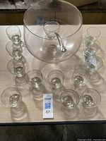 Full set showing punch bowl, ladle inside bowl, and 12 glass cups arranged around it on a table.
