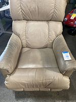 Front view of beige leather recliner chair with visible wear and minor wrinkles