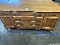 Front view of the wooden buffet showing six drawers and two side cabinets with metal handles, light brown finish.