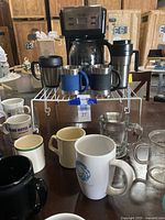 Photo showing MR Coffee 12 cup coffee maker with digital display, glass carafe, and multiple mugs on a table.