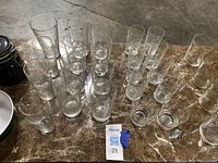 Clear glass drinking glasses of multiple sizes arranged on marble top.